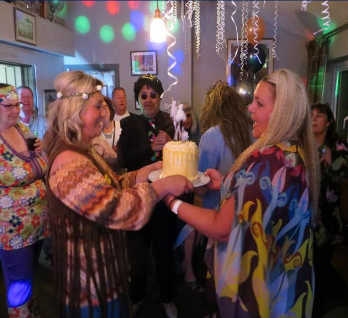 Guests singing together around the birthday cake at a Norfolk party